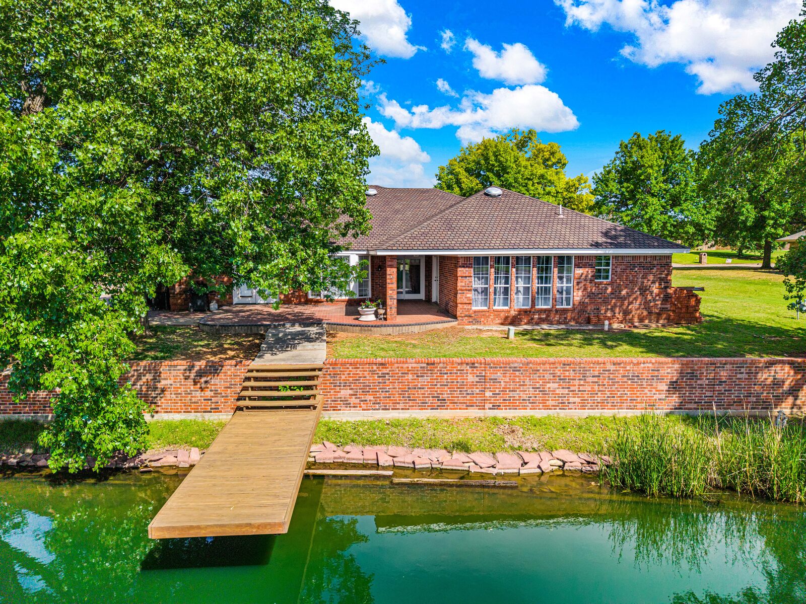 Brick ranch estate in Chickasha — aerial pond-side view