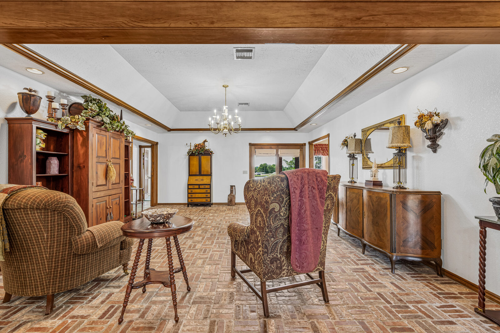Second view of the formal living area showing the brick flooring, traditional furniture, and antique sideboard