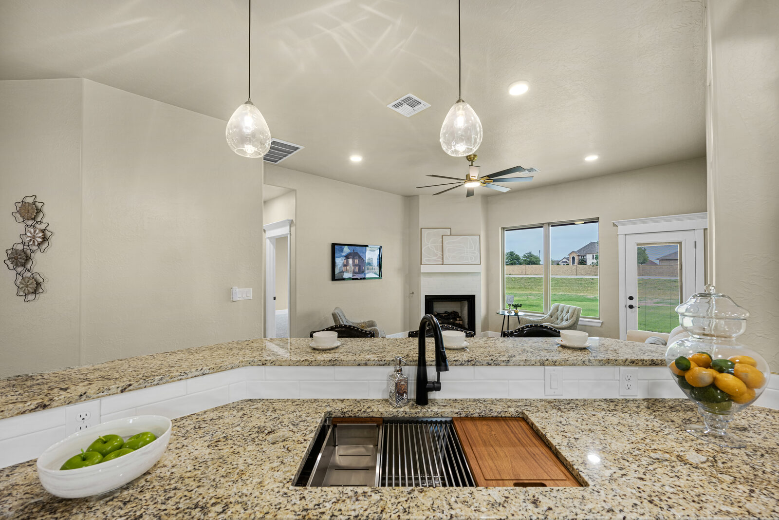 View from the kitchen island across to the living area with vaulted ceiling and stone-front fireplace