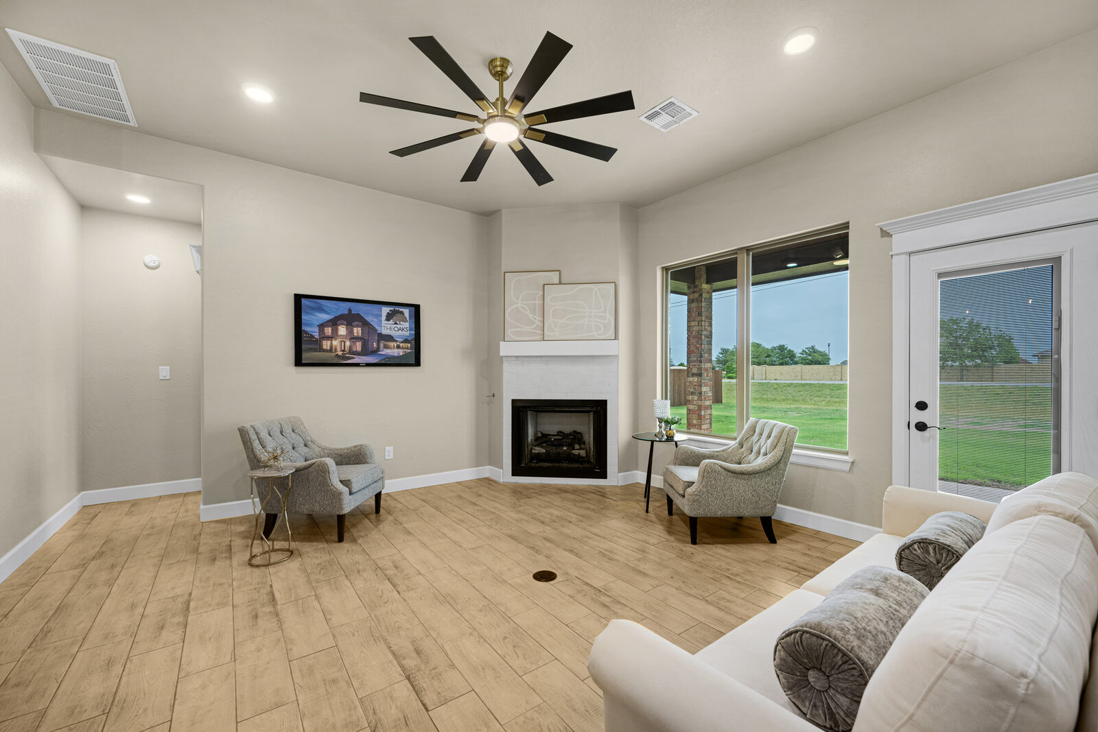 Living room from a second angle showing the fireplace, large windows, and French door to the rear yard