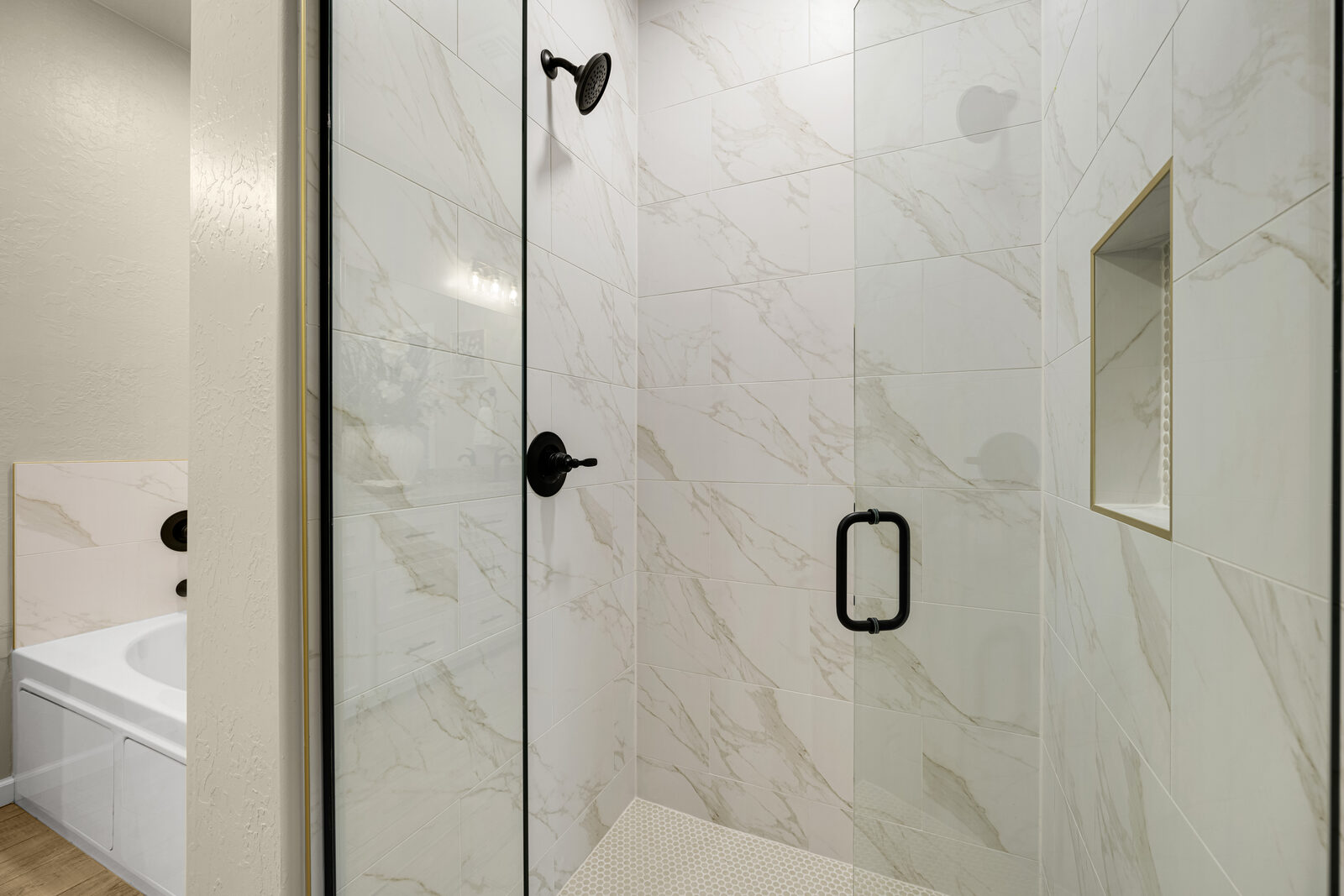 Primary bathroom — large walk-in shower with marble-look tile, oil-rubbed bronze fixtures, and a separate soaking tub
