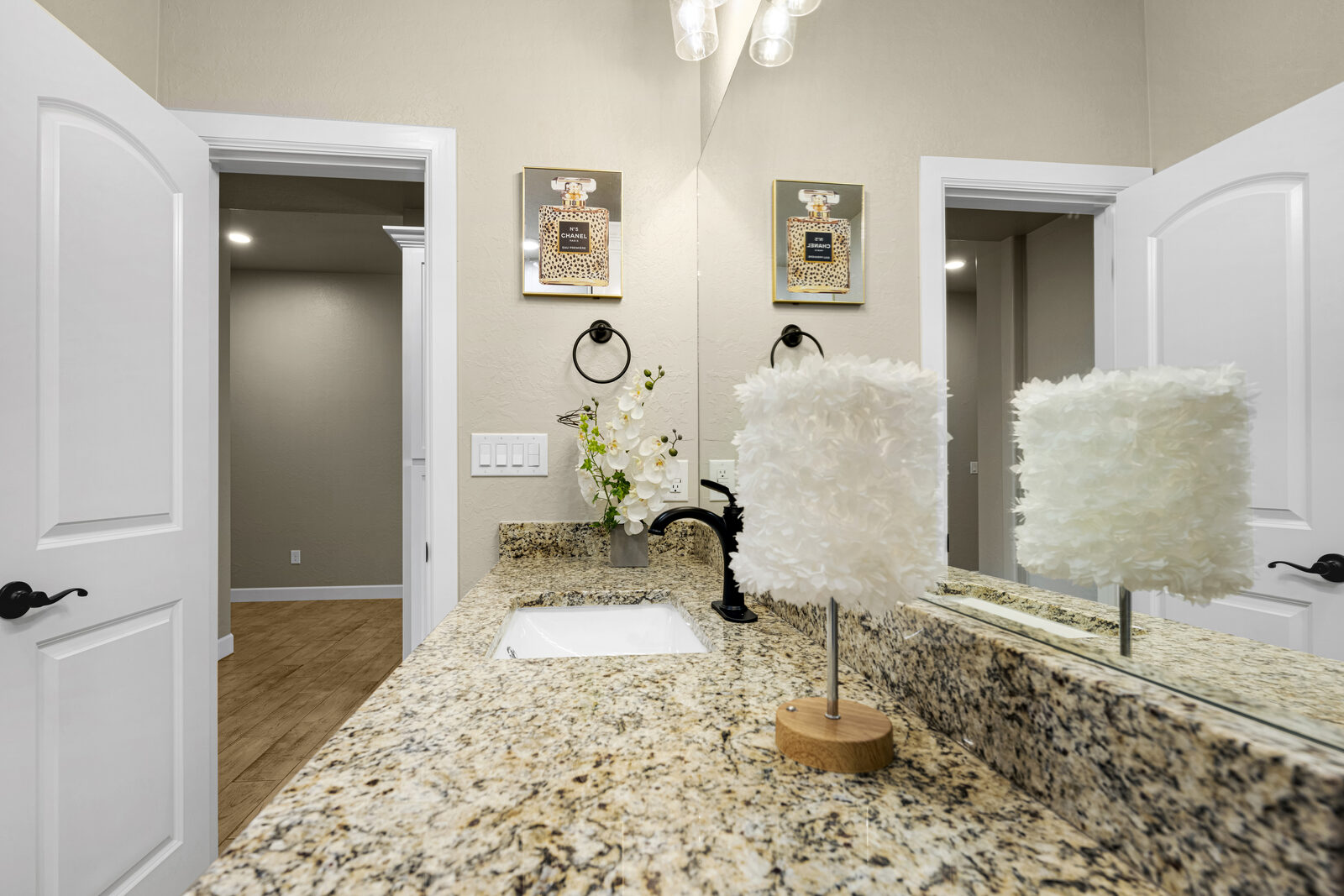 Powder room with granite vanity, matte black faucet, framed art, and tasteful modern staging